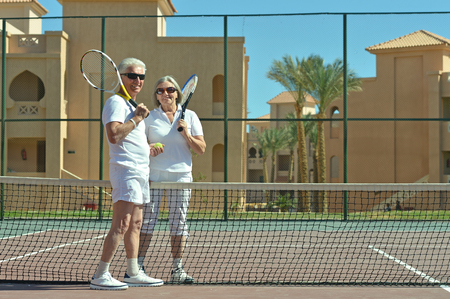 Portrait of a senior couple on tennis courtの写真素材
