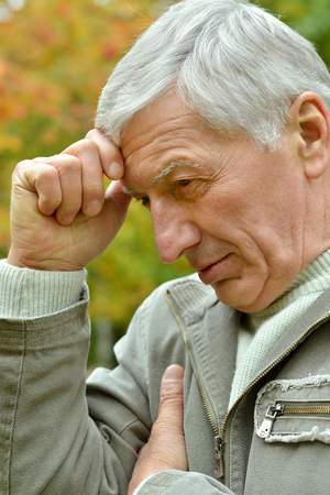 Portrait of thoughtful elderly man in autumnの写真素材