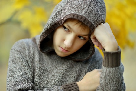 Little sad boy in autumn park