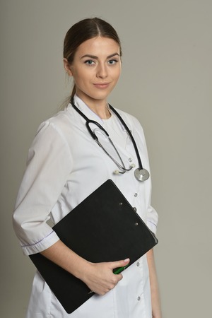 Female doctor with a folder, standing isolated on grey background