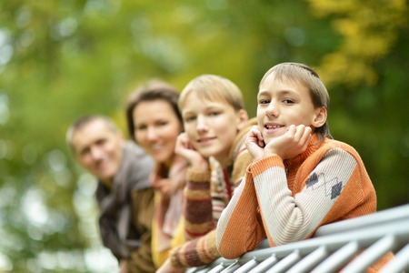 Happy family of four standing together in the park in autumnの写真素材