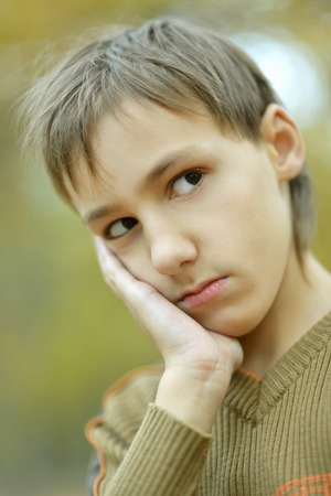 Little sad boy in a warm sweater for a walk in the autumnの写真素材