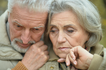 Portrait of a sad senior couple in autumn parkの写真素材
