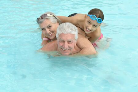 Happy Elderly couple resting at pool  together with grandson