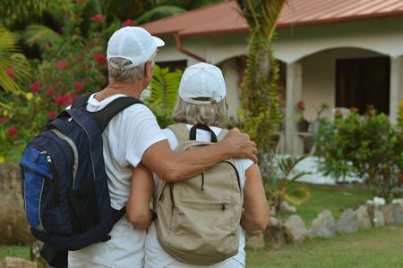 Beautiful happy elderly couple rest at tropical resort with backpacksの写真素材
