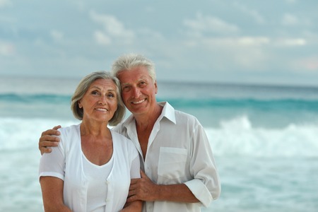 Happy cute senior couple at sea on sunsetの写真素材