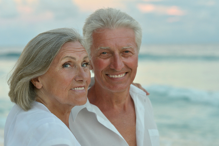 Happy cute senior couple at sea on sunsetの写真素材