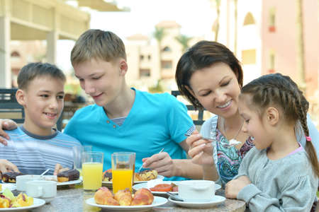 Happy mother and children  at breakfast on tropical resortの写真素材