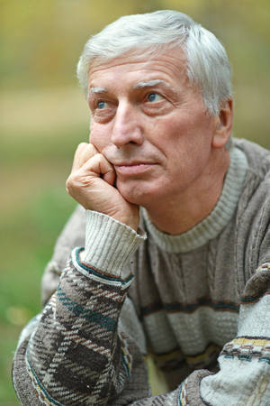 Portrait of thoughtful elderly man in autumnの写真素材