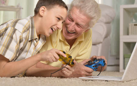portrait of  boy and  grandfather with a laptop,playing computer game at homeの写真素材