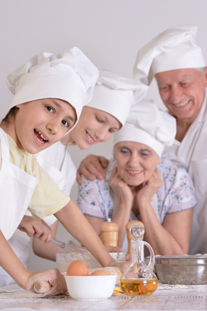 An elderly couple and their grandson knead the dough for the pie togetherの写真素材