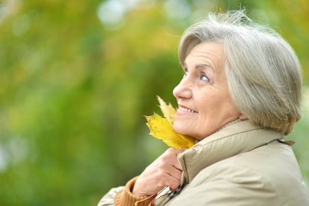 Portrait of smiling senior woman in autumn parkの写真素材