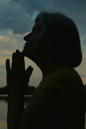 Portrait of a praying olderly woman close-upの写真素材