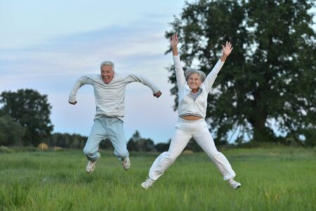 Happy beautiful senior couple exercising  in summer fieldの写真素材