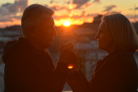 Silhouettes of elderly couple in love over sunset skyの写真素材