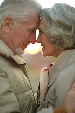 Happy elderly couple at nature on sunset backgroundの写真素材