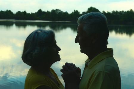 Silhouette of an elderly couple in love at night riverの写真素材