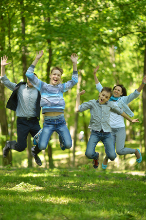 Portrait of a happy family jumping in parkの写真素材