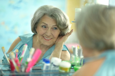 Senior woman in a bathroom with creamの写真素材