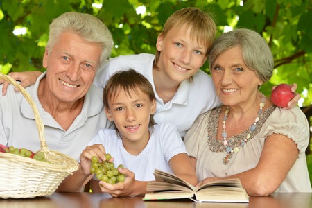 Grandparents with grandsons reading in summer at tablereading in summer at tableの写真素材