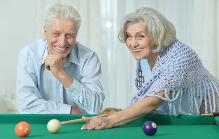 Amusing old couple on vacation playing billiard
