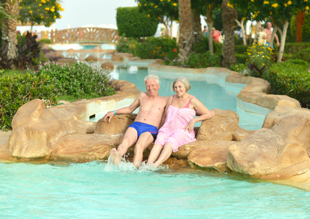 Senior couple relaxing at pool at hotel resortの写真素材