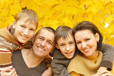Happy family relaxing in autumn park togetherの写真素材