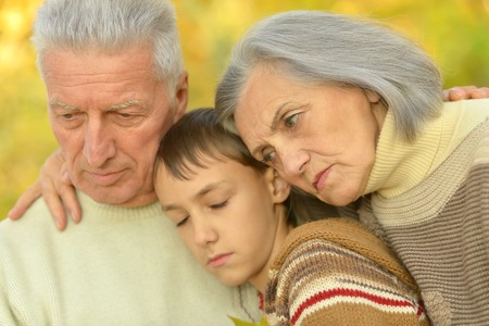 Sad grandparents with boy in the autumn parkの写真素材