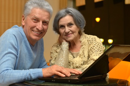 happy senior couple with laptop  in roomの写真素材