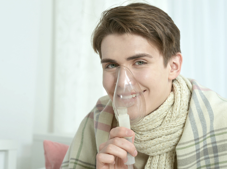 Portrait Of Young Man Inhaling Through Inhaler Maskの写真素材