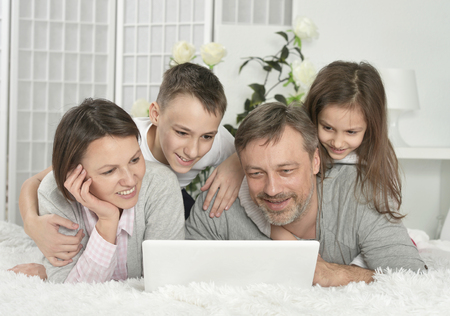 Happy family sitting with laptop at home