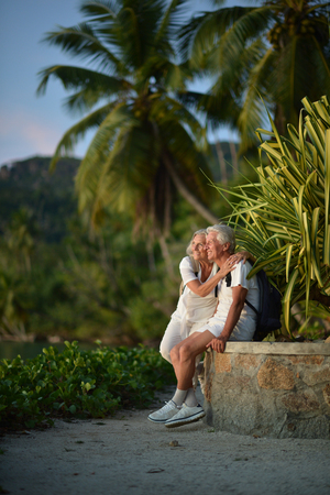 Happy elderly couple with backpacks   in tropical garden outdoorの写真素材