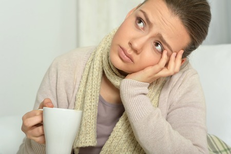 Portrait of a young sick woman drinking hot teaの写真素材