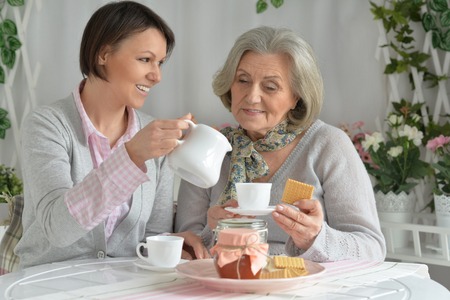 Senior woman with daughter  with tea and foodの写真素材