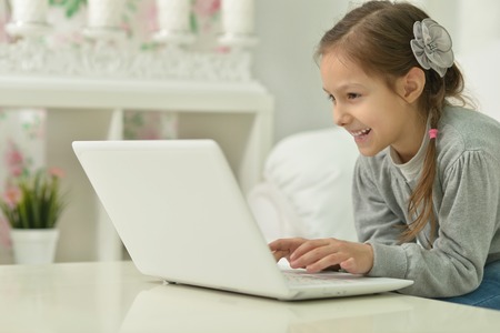 smiling little girl with laptop computer  at homeの写真素材