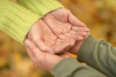 Elderly couple holding hands in autumn parkの写真素材