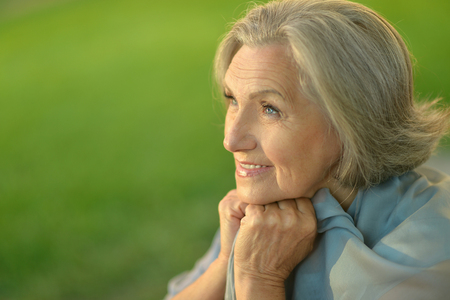 Nice smiling old woman on the green leaves backgroundの写真素材