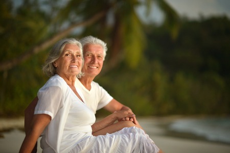 Happy elderly couple rest at tropical beachの写真素材