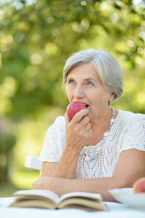 Portrait of a beautiful middle-aged woman outdoors at the table reading a bookの写真素材
