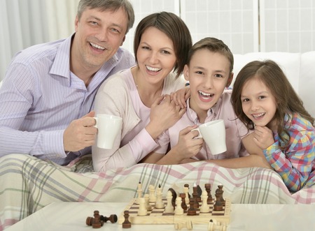 Portrait of a happy family playing chess at homeの写真素材