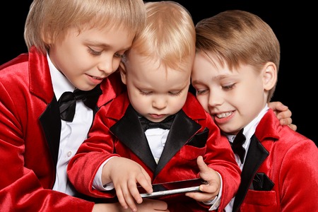 Handsome   little boys in a tuxedo with mobile on black backgroundの写真素材