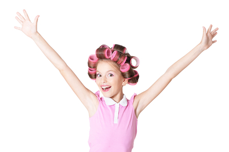portrait of happy Little pretty girl   in hair curlers with hands up in studioの写真素材