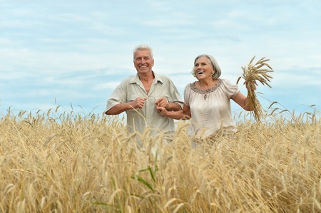 Beautiful happy senior couple in summer fieldの写真素材