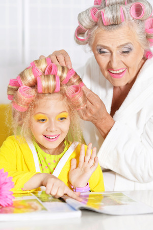 Senior woman and granddaughter doing hairstyle at homeの写真素材