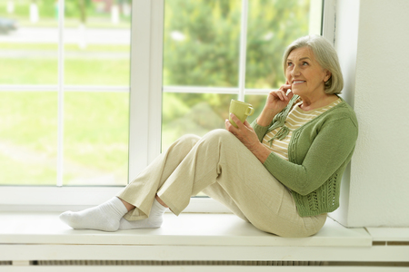happy Senior woman portrait with cup of tea at homeの写真素材