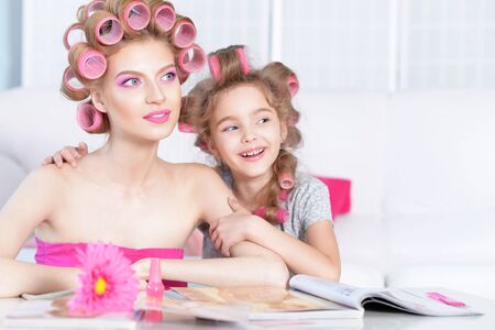 portrait of happy  Mother and little daughter in hair curlers at homeの写真素材
