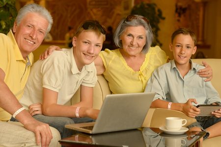 Portrait of a happy boys with grandparents and laptopの写真素材