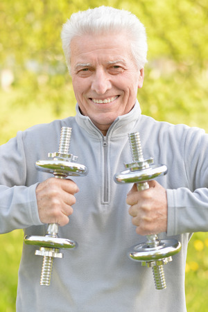 Elderly man exercising with dumbbells in  parkの写真素材
