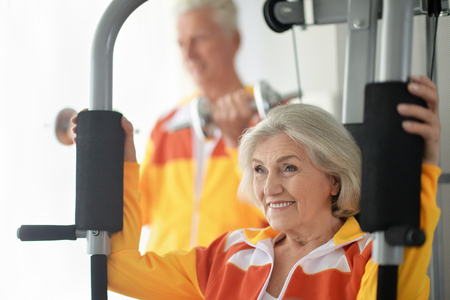 Active smiling senior couple exercising in gym