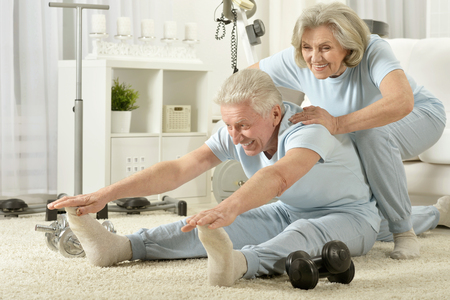Active smiling senior couple exercising at homeの写真素材